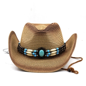 Detail of western straw cowboy hat featuring ethnic beads and turquoise centerpiece
