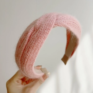 Detail of pink knitted plush cross headband with warm fuzzy mohair texture