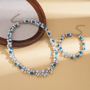Detailed view of elegant pearl and blue gemstone necklace and bracelet set on beige surface
