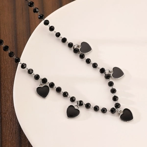 Detailed close-up of gothic black beaded necklace with silver-edged heart pendants on a tray