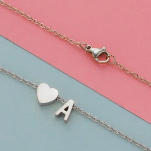 Macro view of silver stainless steel heart pendant and letter A charm necklace with lobster clasp