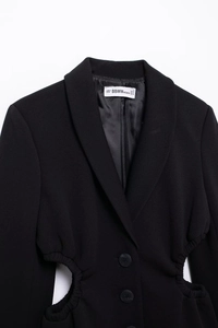 Detail of black blazer featuring shawl collar, single button and side waist cutout design