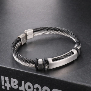Twisted steel cable bracelet in black and silver with matte metal accents on display