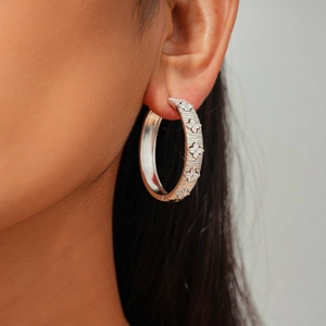 Detail of silver-plated hoop earring with brushed metal finish and floral zircon pattern
