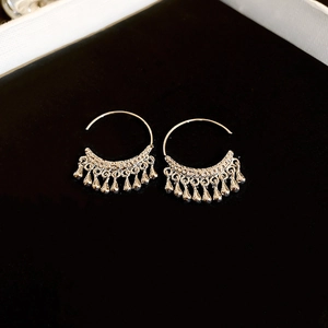Detailed macro view of silver C-shaped metal tassel earrings with waterdrop charms