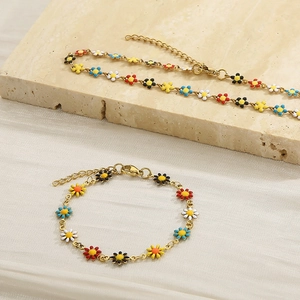 Detail of gold chain necklace and bracelet set with colorful enamel daisy pendants