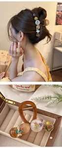 Détail de la pince à cheveux en résine ambrée avec perles de fleurs séchées et feuille