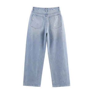 Détail d'un pantalon en jean bleu clair à jambes larges avec décor strass brillant