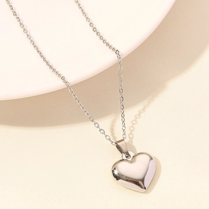 Polished silver heart pendant necklace on a minimalist ceramic plate display