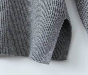 Close-up of light gray ribbed knit sweater hem featuring a stylish side slit detail