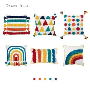 Detail of six tufted cushion covers with colorful geometric patterns and corner tassels