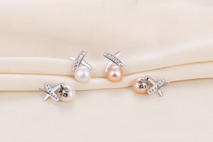 Macro detail of white and pink freshwater pearl earrings with silver criss-cross zircon settings