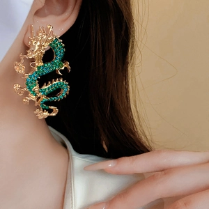 Dettaglio di ear cuff a forma di drago placcato oro con strass verdi sul modello