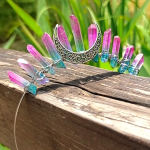 Detailed view of handmade pink and teal crystal moon crown headband on a wood background