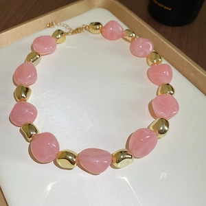 Detailed shot of irregular pink acrylic beads and golden beads on a vintage necklace