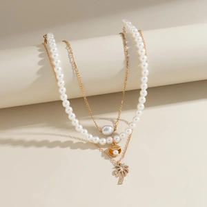 Detailed close-up of layered pearl necklaces with golden shell and palm tree charms