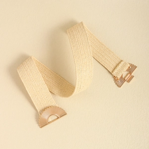 Detailed view of beige woven elastic waist belt featuring a gold scalloped metal buckle