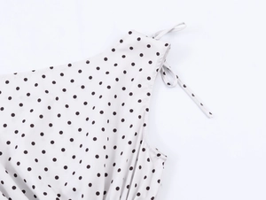 Detail of white top with black polka dots featuring a delicate shoulder tie knot