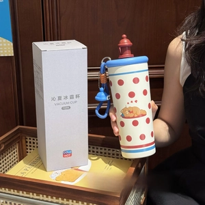 Detail of cute bear thermos with blue strap and colorful box on a cozy wooden surface