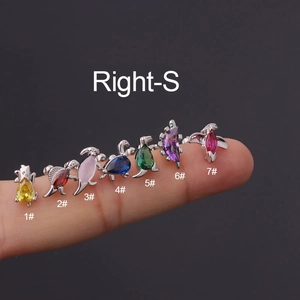 Detailansicht von 7 Dinosaurier-Ohrsteckern mit bunten Zirkonia auf einem Finger gezeigt