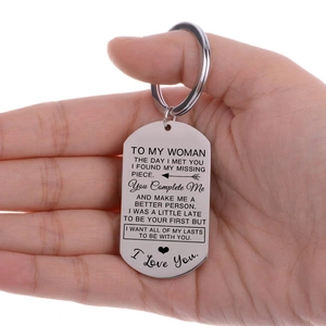 Nahaufnahme eines Edelstahl-Schlüsselanhängers mit TO MY WOMAN Gravur in der Hand