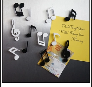 Musical note magnets holding a memo and banknote on a metallic brushed surface
