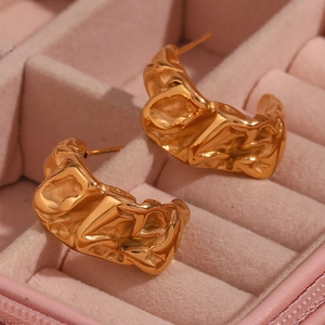 Detailed close-up of gold moon-shaped earrings with irregular texture in a velvet box