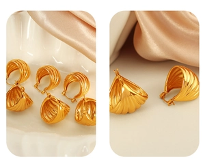 Detail of golden striped hoop earrings featuring elegant shell texture on silk fabric