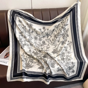 Detail of a large silk scarf with black and white floral prints on a leather sofa