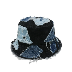 Detailed close-up of dark blue denim bucket hat with frayed patchwork and vintage stitching