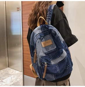 Detail of vintage patchwork denim backpack with white stitching and leather zipper pulls