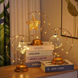 Macro shot of three gold crescent moon LED lamps with star and bulb ornaments on a book
