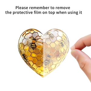 Detail view of removing protective film from heart bee acrylic ornament with golden patterns