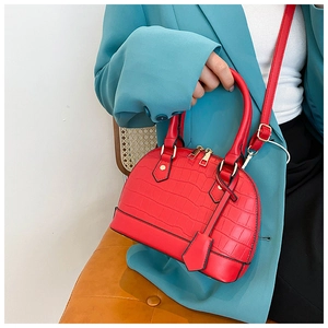 Detail of red crocodile texture shell bag with adjustable strap and metallic zippers
