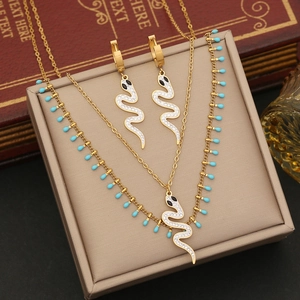 Macro detail of gold snake pendant with diamonds and turquoise beads on double chain