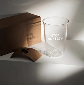 Close-up of heat-resistant glass cup with cat illustration and Stop Anxiety text