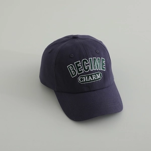 Detail of navy blue cotton baseball cap featuring green and white CHARM 3D embroidery