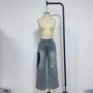 Close-up of low-rise jeans with distressed holes and dark blue side patchwork details