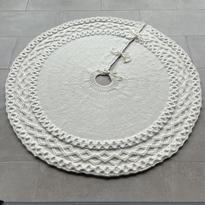 Detail of cream white knitted Christmas tree skirt with diamond patterns and ties