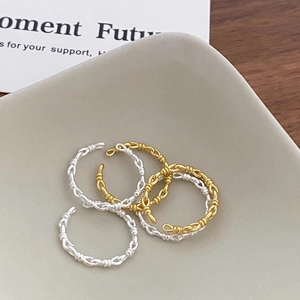 Detailed view of silver and gold braided knot rings on a minimalist wooden display
