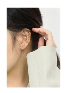 Close-up of minimalist gold hoop earrings and double-layered ear cuff on model ear
