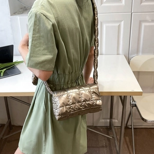 Close-up of golden quilted puffer crossbody bag worn with a green dress