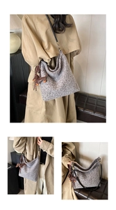 Detail of wool texture bucket bag with leather puppy charm and gold hardware