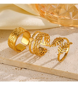 Macro shot of gold stainless steel rings with star and feather patterns on a stone surface