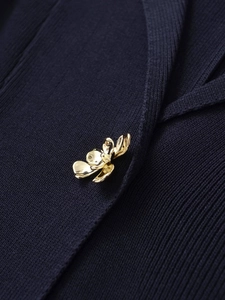 Close-up of golden flower-shaped button on navy ribbed knit fabric for women's top