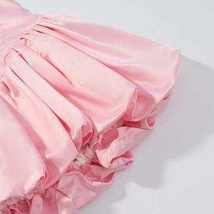 Detailed view of pink satin ruffled dress hem with elegant pleated texture and glossy finish