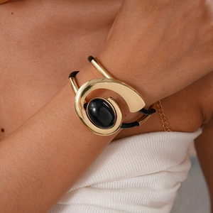 Detail of a vintage oval black gemstone set in a golden spiral metal frame on a woven cord