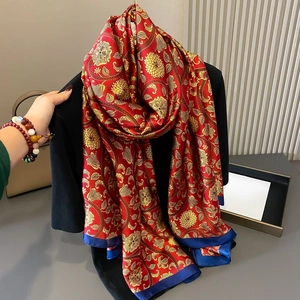 Detailed view of red silk scarf with golden peony floral print and blue hem contrast