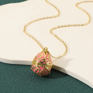 Elegant gold egg pendant necklace with pink enamel and intricate filigree patterns