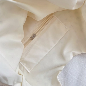 Detail of the cream canvas shoulder bag featuring an internal zip security pocket